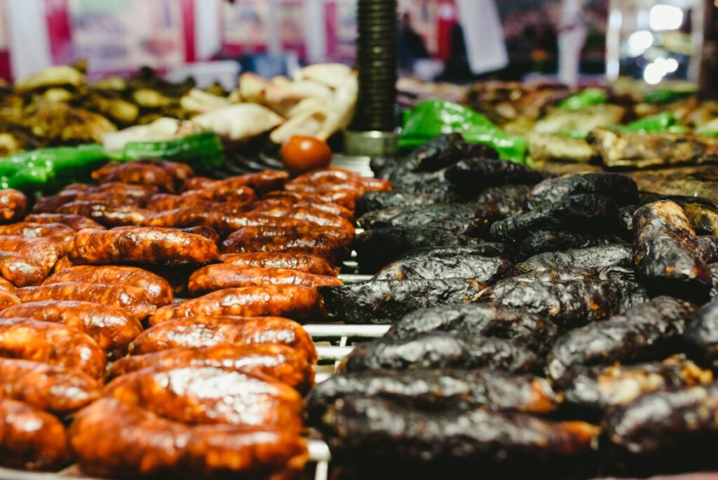 Rows of red and dark sausages arranged on display at a market stall, ready for sale.